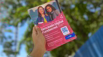 Mão feminina segurando folder referente ao Simulado Digital da Fundacred.