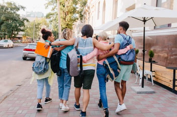 Estudantes abraçados caminhando pela rua.