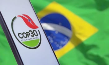 Um celular e no fundo uma bandeira do Brasil.