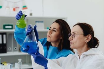 Professou e aluna analisando frascos em laboratório.