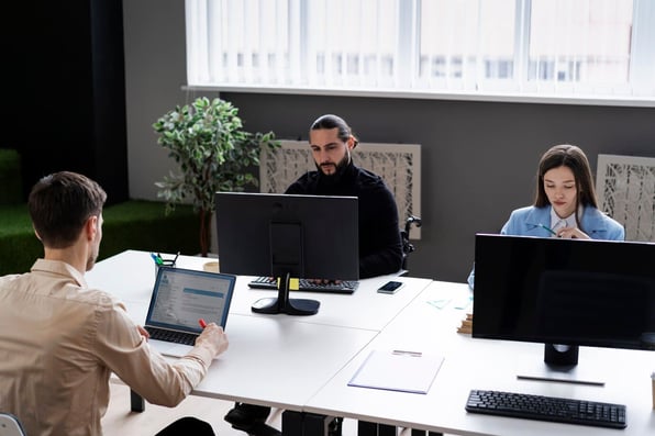 Colaboradores em frente a computadores no escritório. 