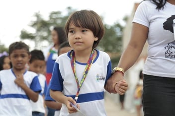 Criança autista caminhando de mãos dadas.