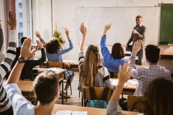 Pessoas levatando as mãos para responder ao professor