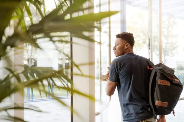 Jovem negro de mochila saindo em uma porta