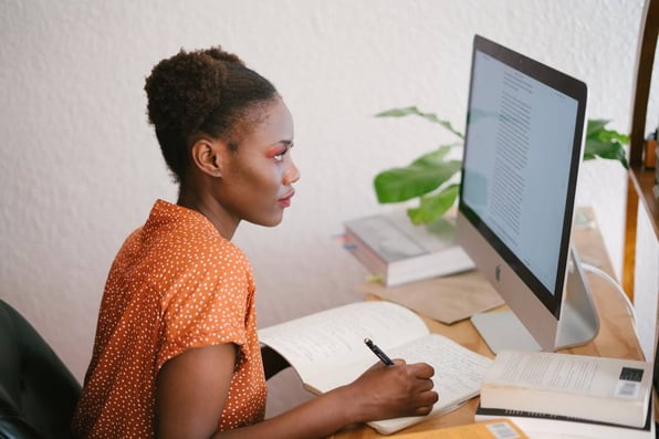 Mulher em frente a um computador com um bloco de notas