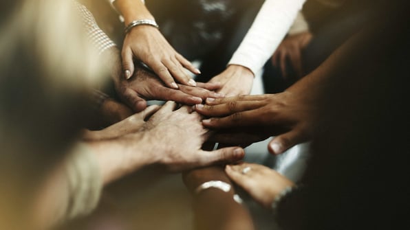 Diversas mãos unidas ao centro de uma roda