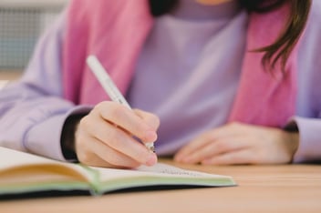 Menina escrevendo em seu caderno.