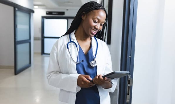 Estudante de medicina com jaleco segurando tablet.
