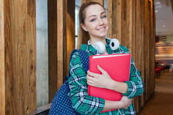 Estudante com fone de ouvido no pescoço e caderno na mão