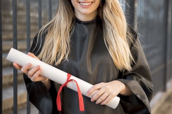 Mulher sorrindo, segurando um diploma