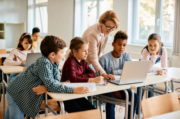 Professora ajudando alunos com computador