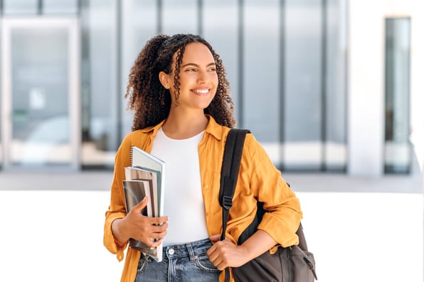 Mulher negra com mochila nas costas e segurando livros.