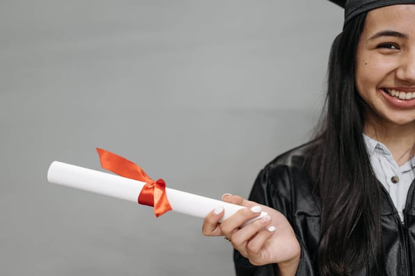 Menina sorridente vestindo toga e segurando diploma 