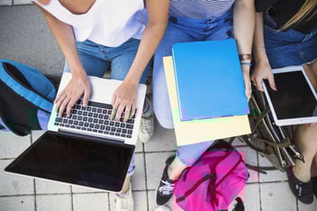 Pessoas segurando no colo notebook e livros.