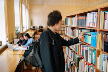 Estudante na biblioteca procurando um livro.