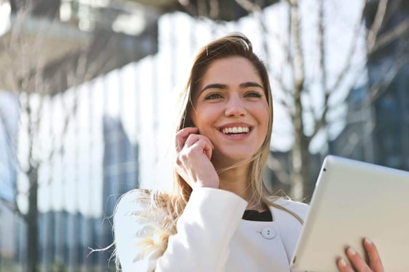 Mulher segurando um tablet enquanto fala ao telefone