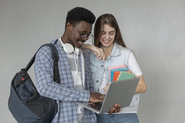 Dois jovens estudantes olhando algo em notebook.