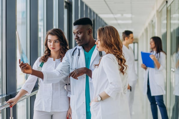 Grupo de jovens médicos analisando um exame de imagem.